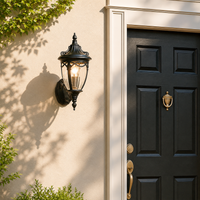Traditional black aluminum teardrop glass wall lantern on beige stucco facade next to black front door for porch decor.
