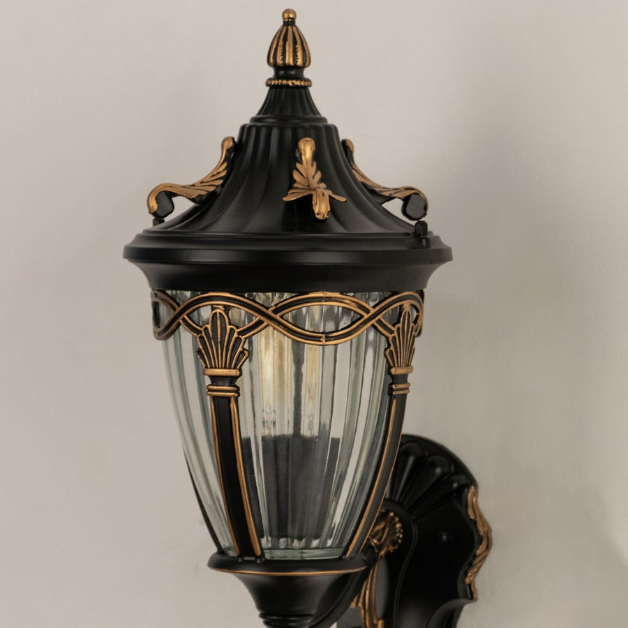Closeup of bronze outdoor wall lantern showcasing ribbed clear glass ornate bronze detailing and a classic top design ideal for enhancing porch and patio decor.