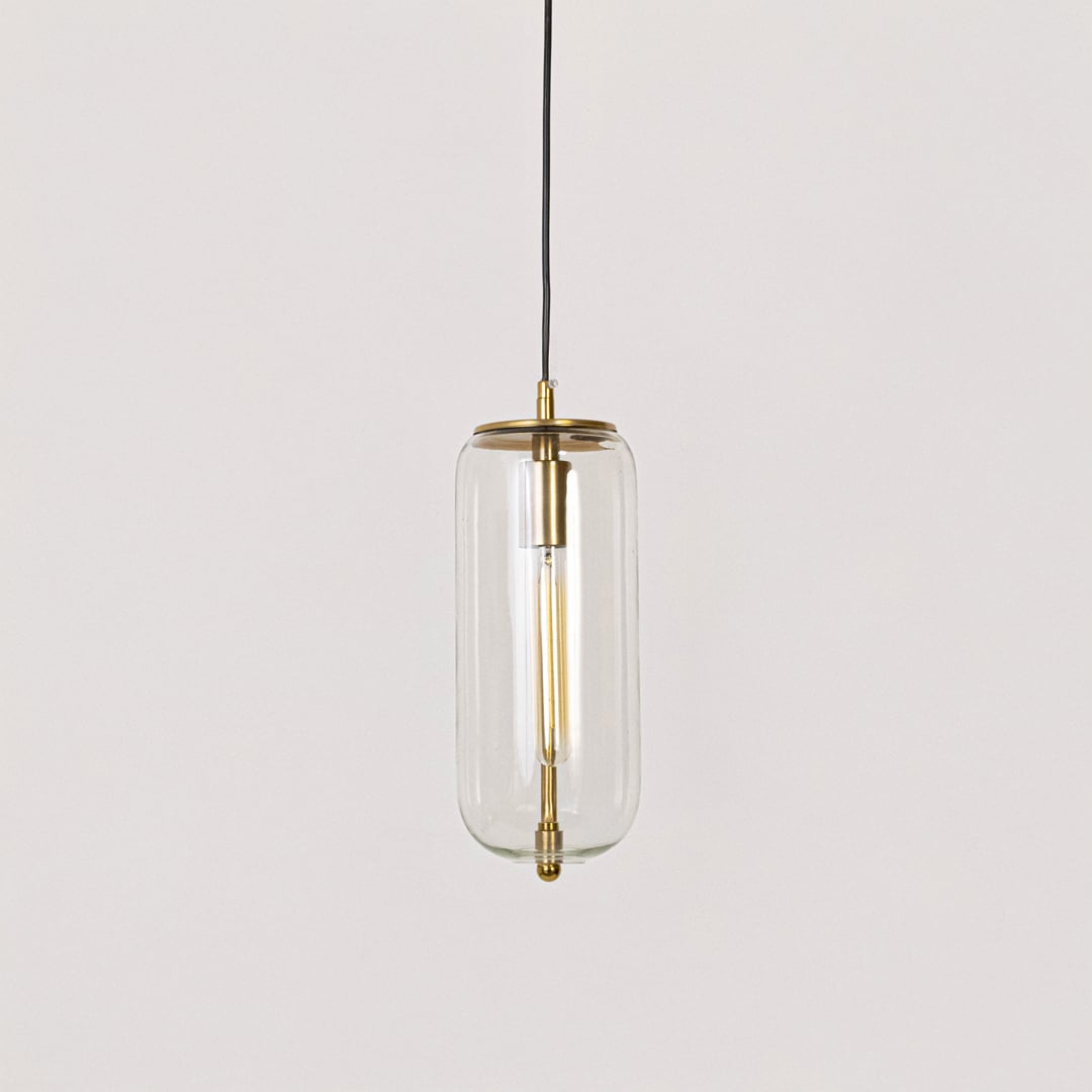 Pendant light with gold finish and clear cylindrical glass shade shown switched off on plain white background.