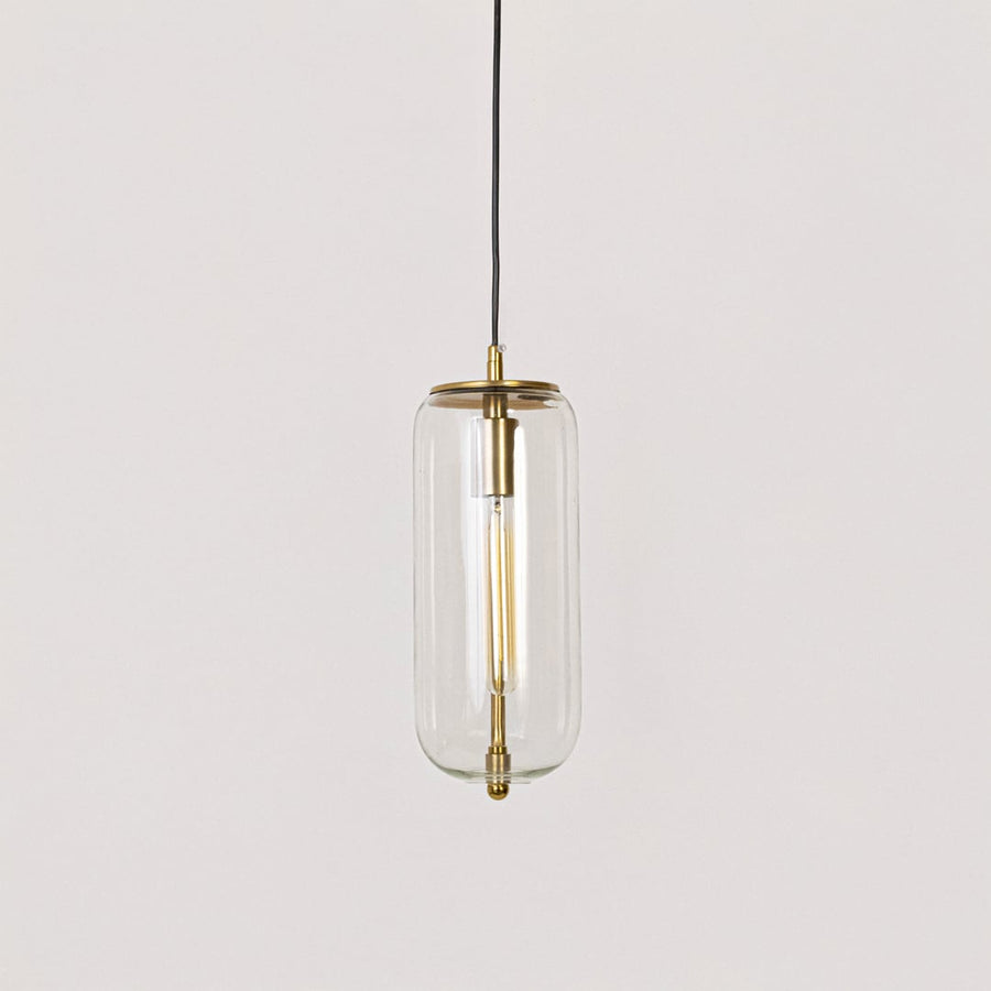 Pendant light with gold finish and clear cylindrical glass shade shown switched off on plain white background.