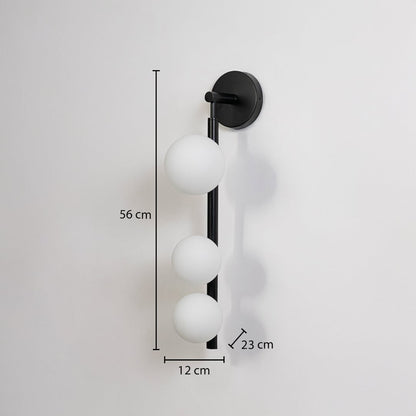 Black wall sconce with three frosted glass globes shown with size 56 cm height 12 cm width 23 cm depth for accurate fitting details.