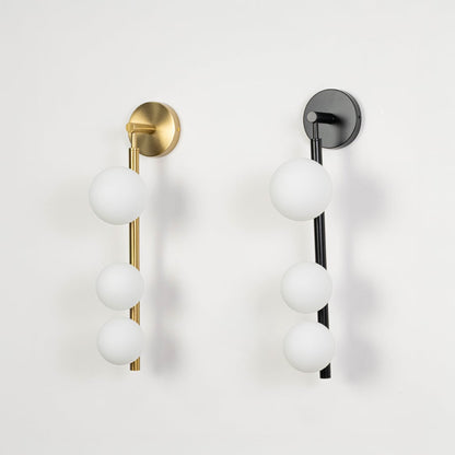 Pair of gold and black wall sconces with three frosted glass globes switched off displayed on plain white background product showcase.