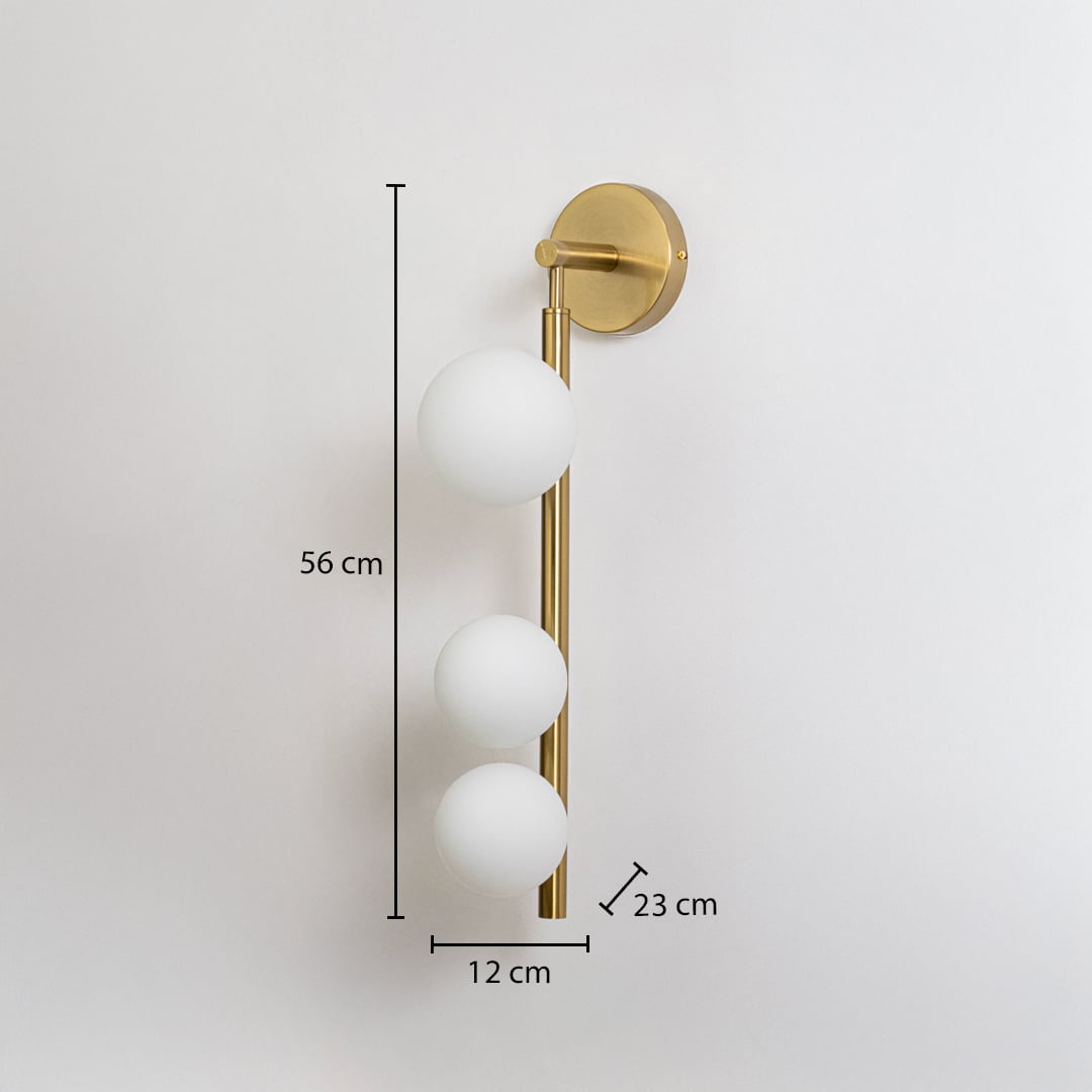 Gold wall sconce with three frosted glass globes shown with size 56 cm height 12 cm width 23 cm depth for accurate fitting display.
