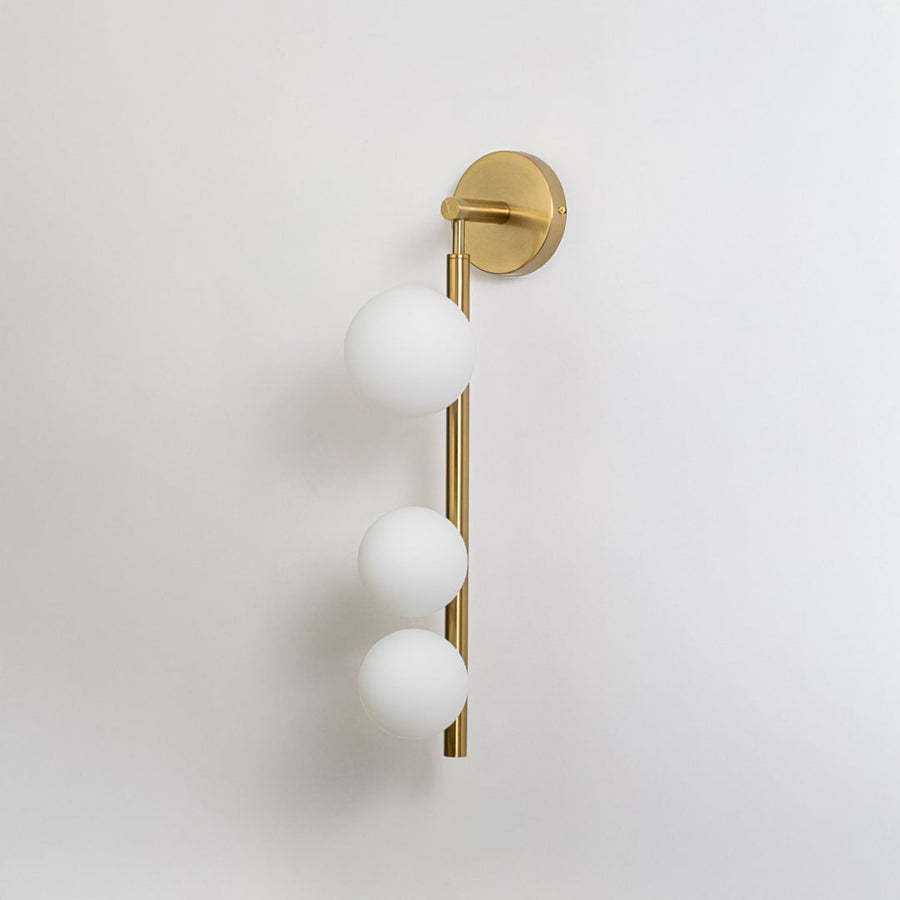 Minimalist gold wall sconce with frosted glass globes switched off displayed on plain white background for product catalog display.