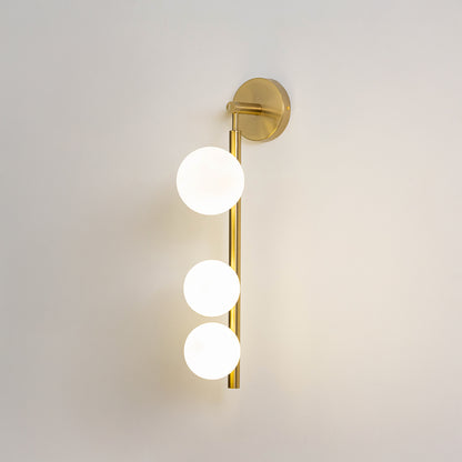 Minimal wall light in gold metal finish with three globe bulbs for bedroom or living room decor lighting white background.