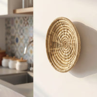 Handcrafted round wall decor in natural woven finish mounted on kitchen wall adding earthy texture and artisanal charm to home interior.
