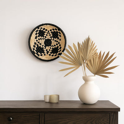 Metal wall decor with bold cutout design paired with dried foliage arrangement creating elegant shelf styling with modern earthy home decor aesthetics.