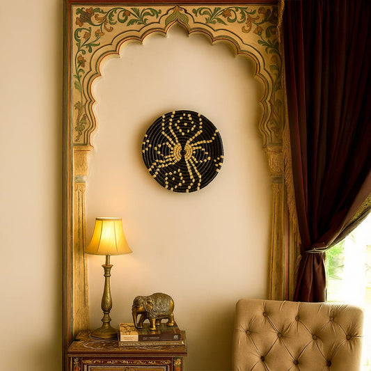 Black pattern wall basket mounted on an ornate beige wall above a side table with lamp and elephant figurine for elegant living room décor.