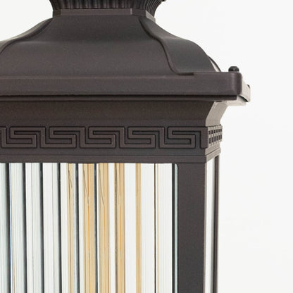 Closeup view of outdoor wall lantern top section showing decorative black metal detailing and vertical glass panels.