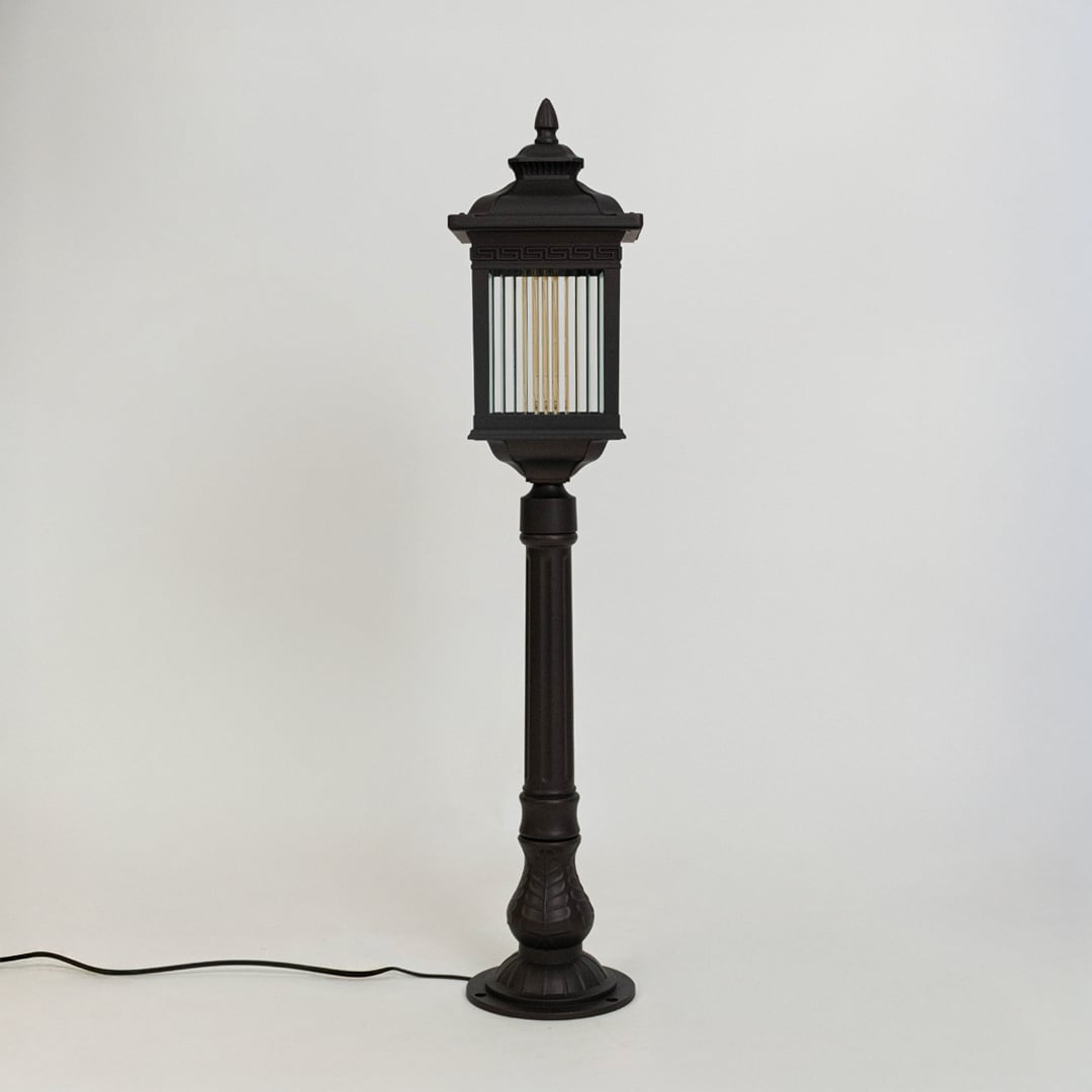 A modern black outdoor bollard light shown on a white background with the light off highlighting its clean rectangular structure clear ribbed glass panels and sturdy base.