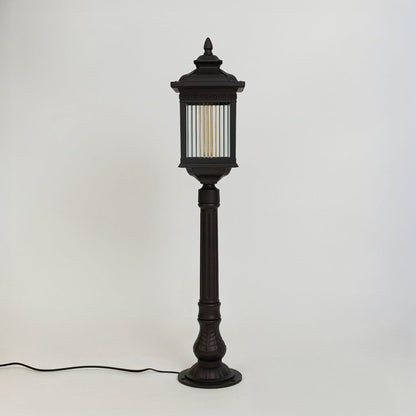 A modern black outdoor bollard light shown on a white background with the light off highlighting its clean rectangular structure clear ribbed glass panels and sturdy base.