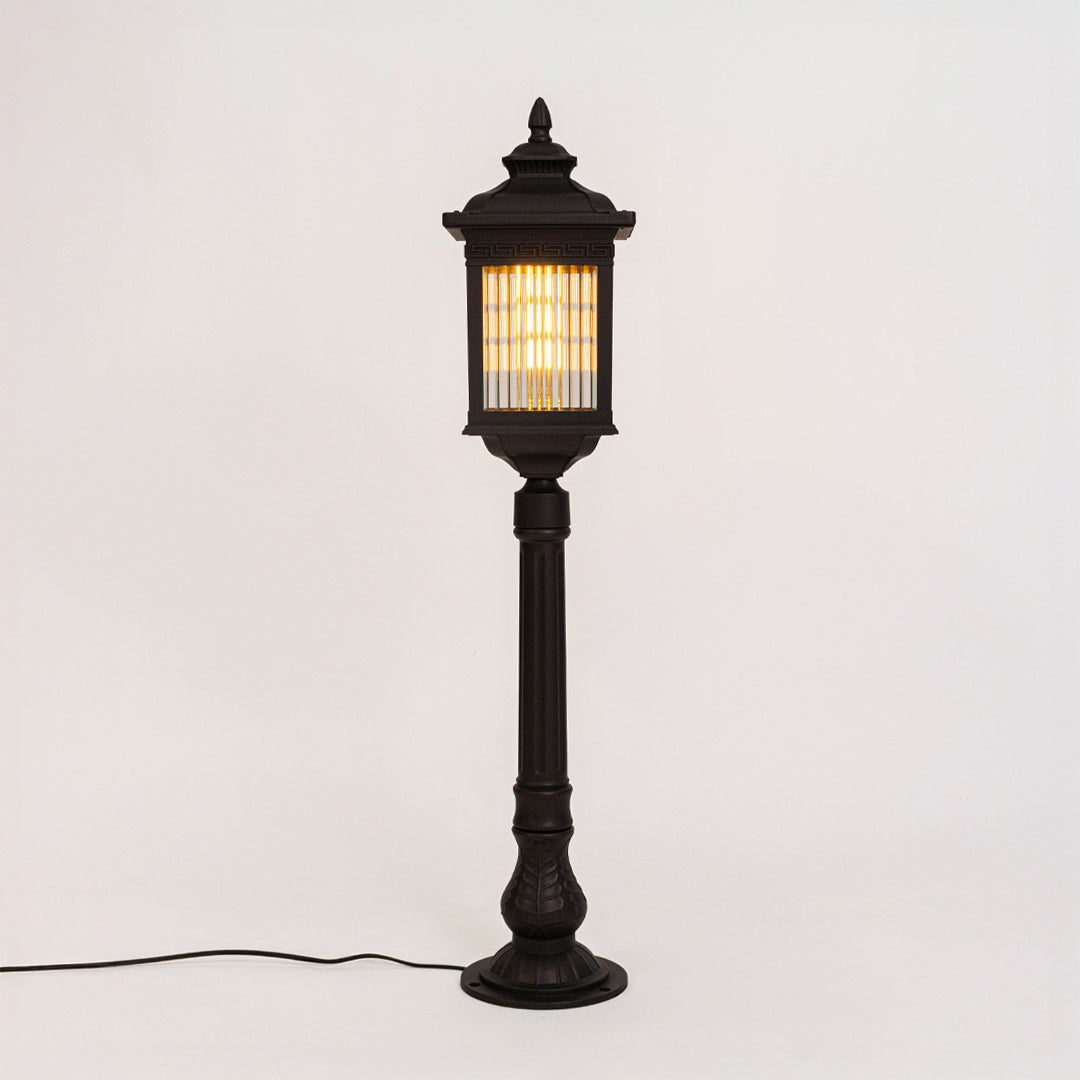 Vintage black outdoor bollard light with warm glowing panels for luxury exterior decor styling use.