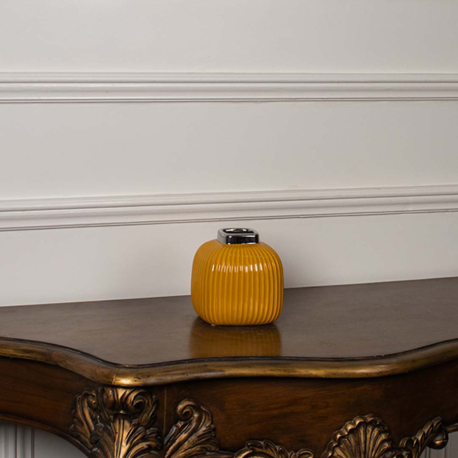 Yellow ribbed ceramic mini vase displayed on a clean white background highlighting its glossy top and modern shape.