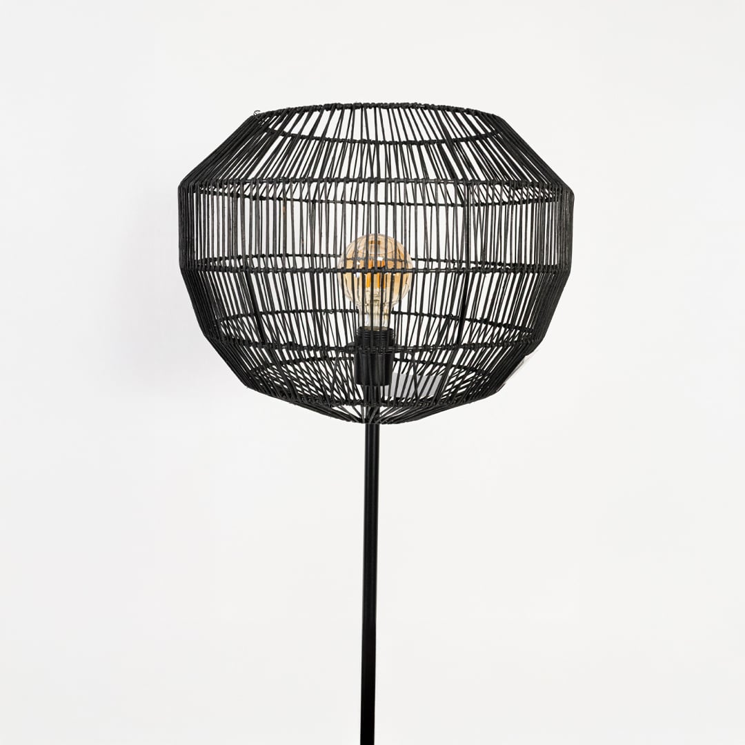 Elegant black rattan floor lamp closeup showing intricate woven shade and warm ambient lighting.