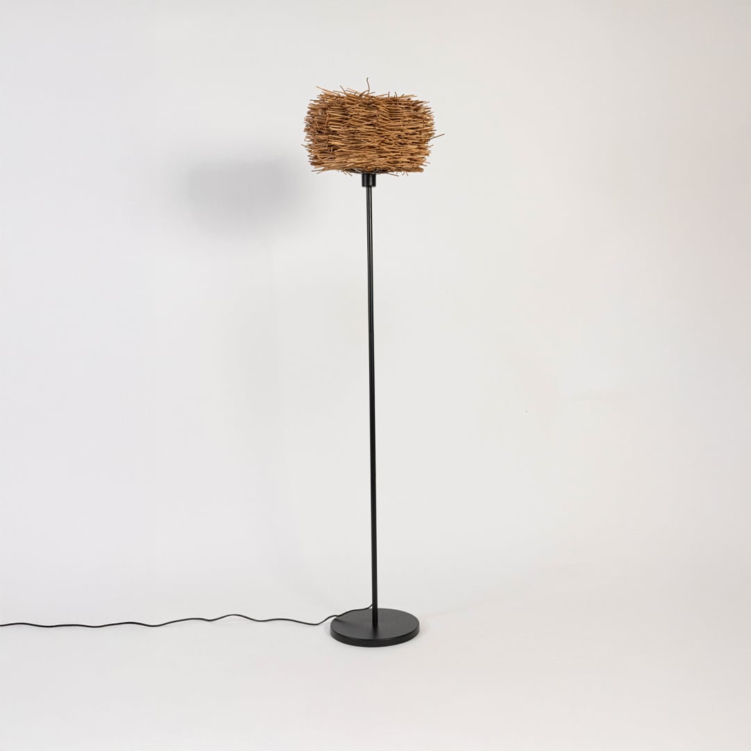 Wicker floor lamp with light off showcasing rattan shade texture and slim black stand.