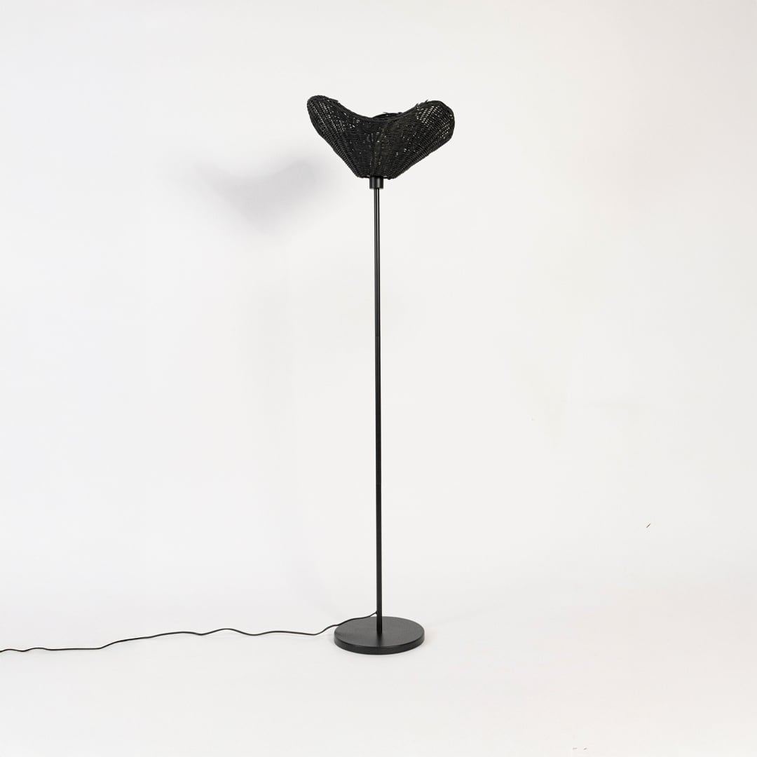 Black floor lamp with sculpted rattan shade switched off on white background stylish decorative accent.