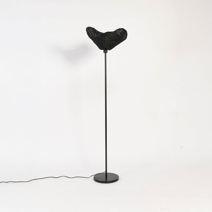 Black floor lamp with sculpted rattan shade switched off on white background stylish decorative accent.