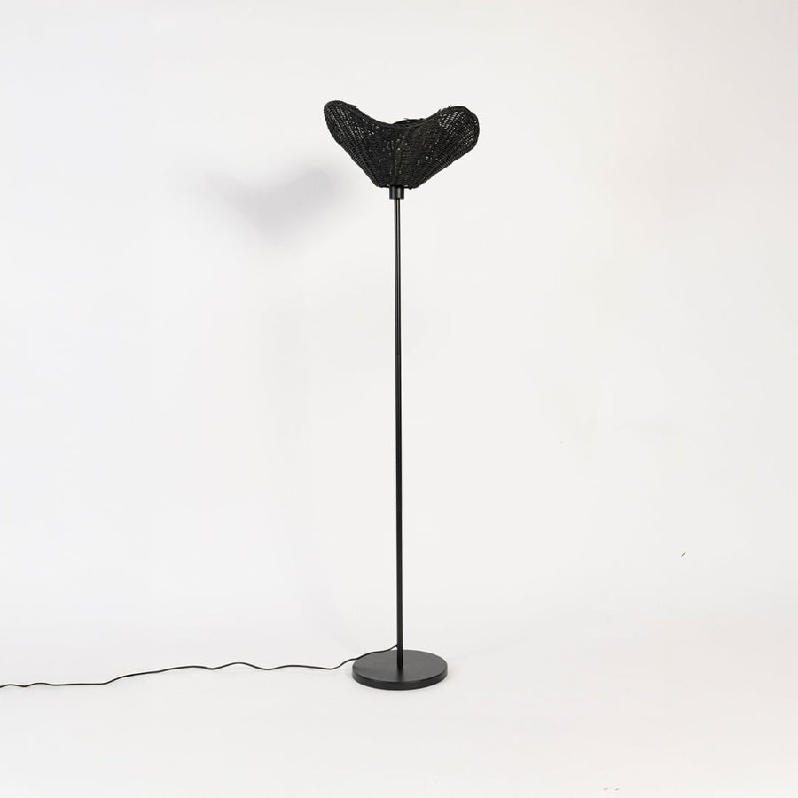 Black floor lamp with sculpted rattan shade switched off on white background stylish decorative accent.