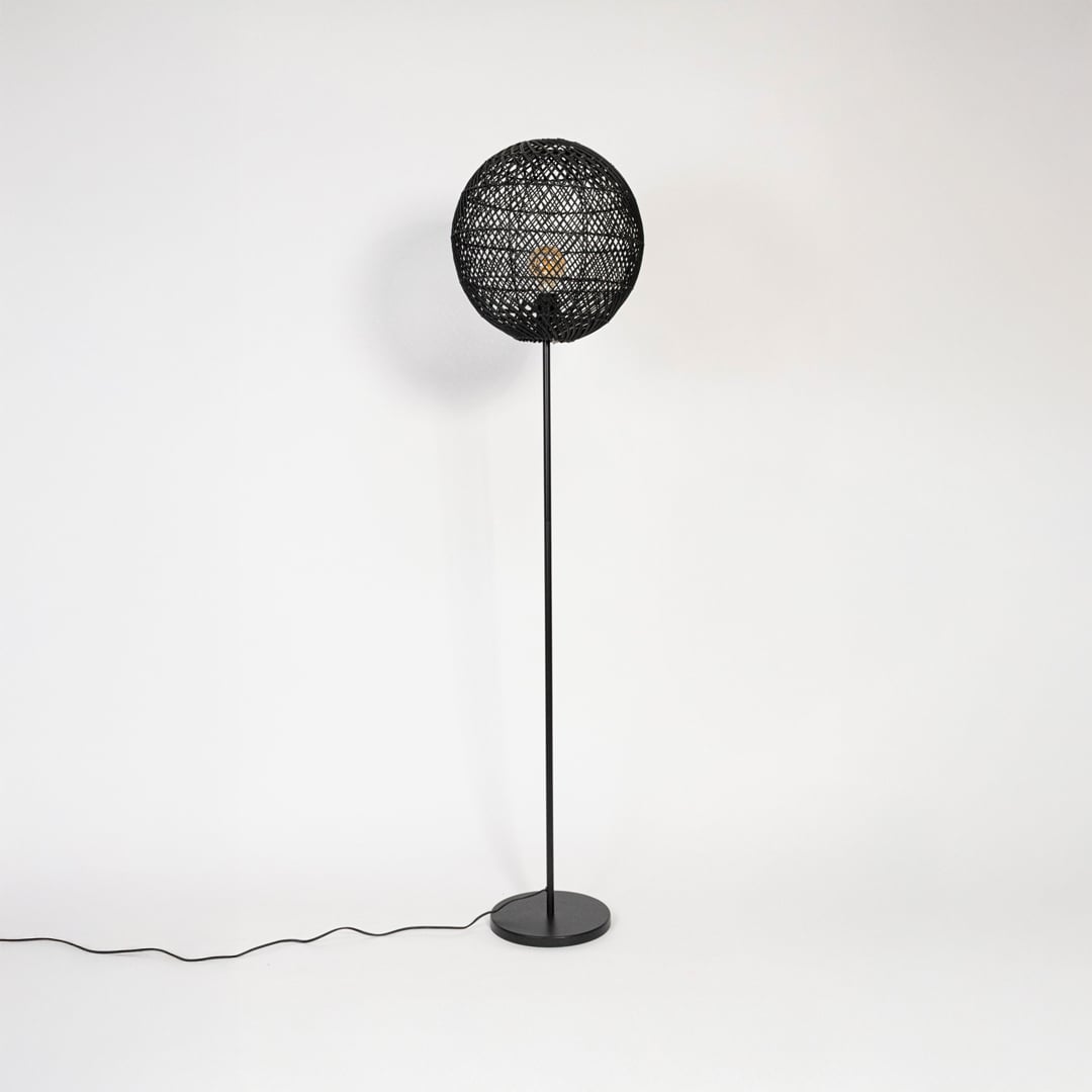 Black floor lamp with woven rattan globe shade turned off on plain white background stylish home accent.
