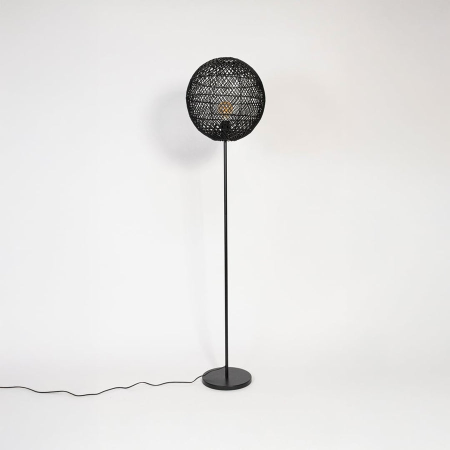 Black floor lamp with woven rattan globe shade turned off on plain white background stylish home accent.