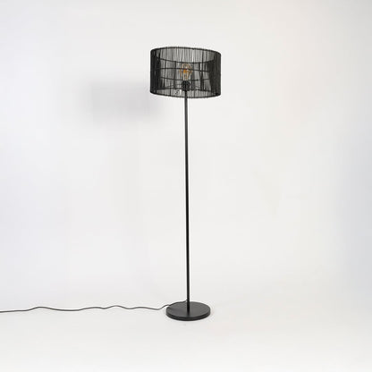 Black floor lamp with woven rattan shade switched off on white background decorative home lighting accent.