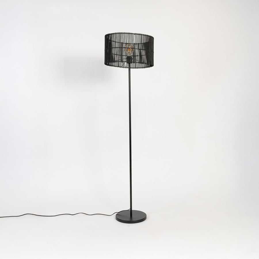 Black floor lamp with woven rattan shade switched off on white background decorative home lighting accent.