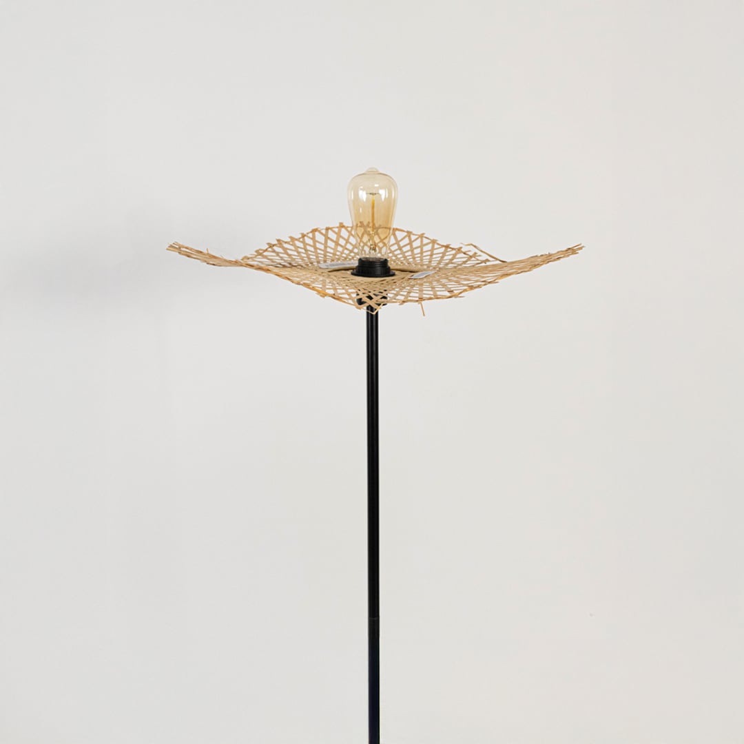 Closeup of black floor lamp with rattan leaf shade showing artisanal woven detailing and modern style.