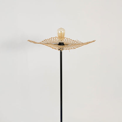 Closeup of black floor lamp with rattan leaf shade showing artisanal woven detailing and modern style.