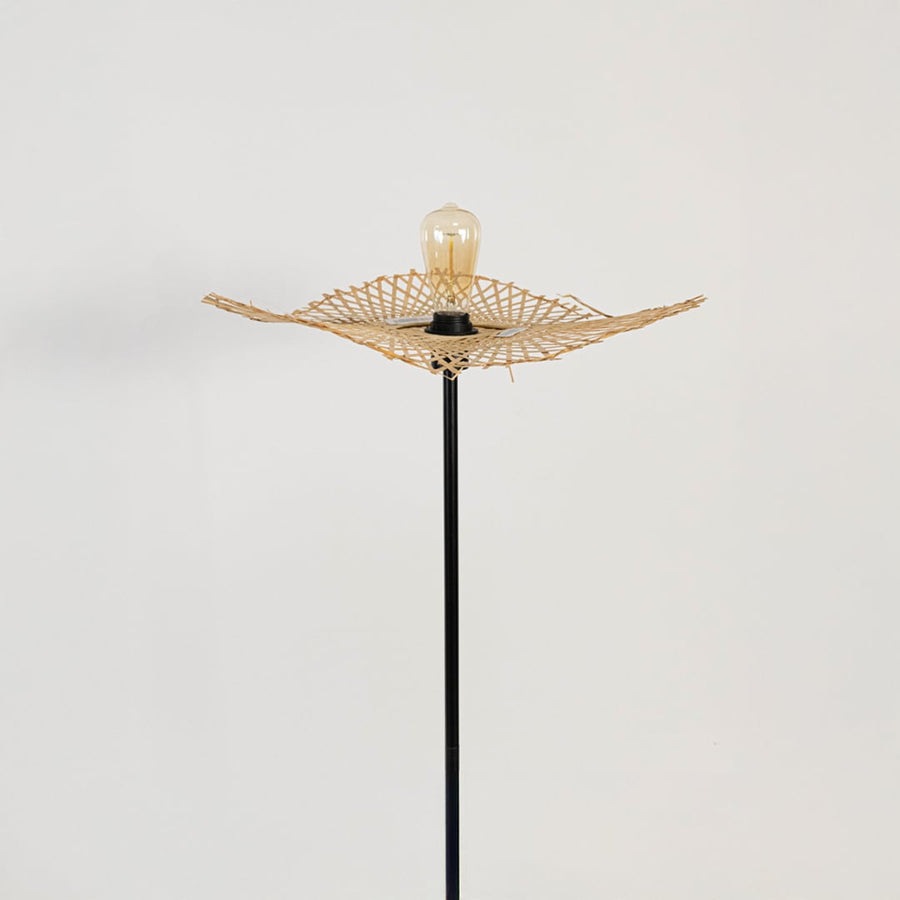 Closeup of black floor lamp with rattan leaf shade showing artisanal woven detailing and modern style.