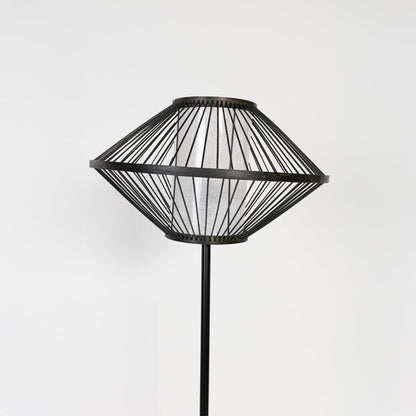 Closeup of black floor lamp with geometric wire shade showing modern design and sleek detailing.