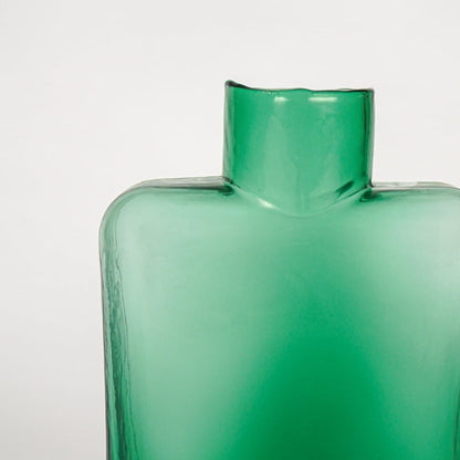 Close up view green art glass vase showing glossy sculpted surface modern decorative glass accent piece for shelf styling home.