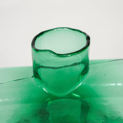 Close up view green art glass vase showing glossy sculpted surface modern decorative glass accent piece for shelf styling home.