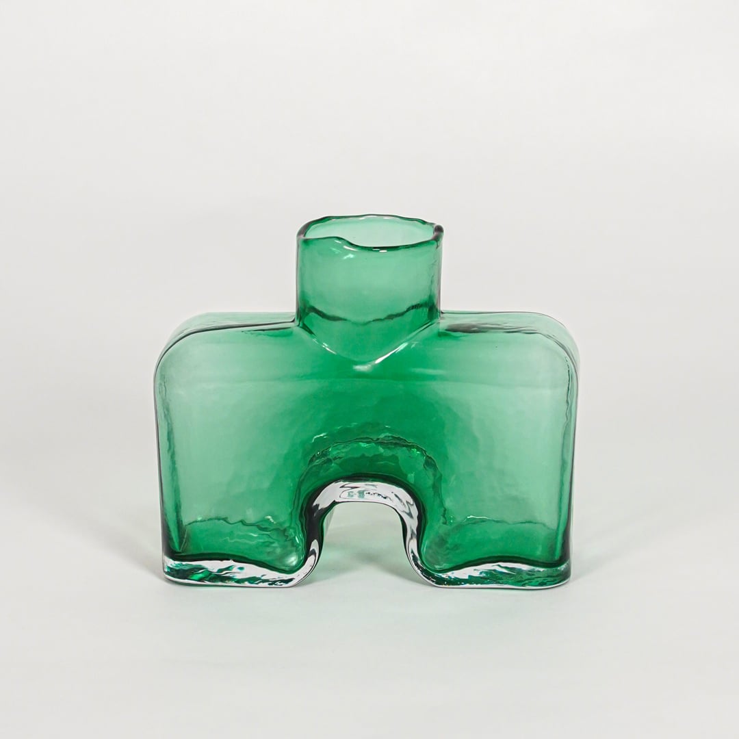 Green decorative art glass vase on white background modern home decor accent piece for table shelf console styling interior.