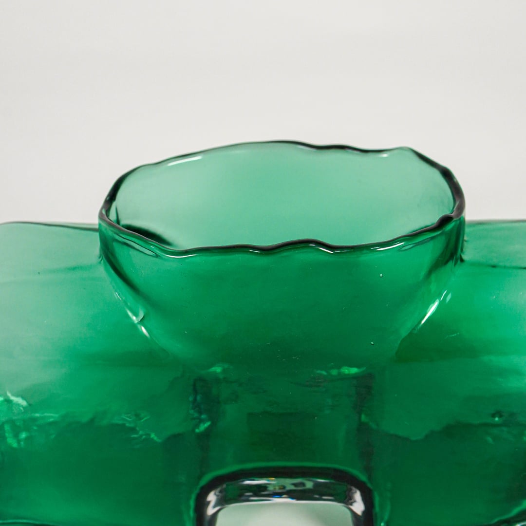 Close up view green art glass vase showing glossy surface sculpted form luxury decorative glass accent for shelf styling home.