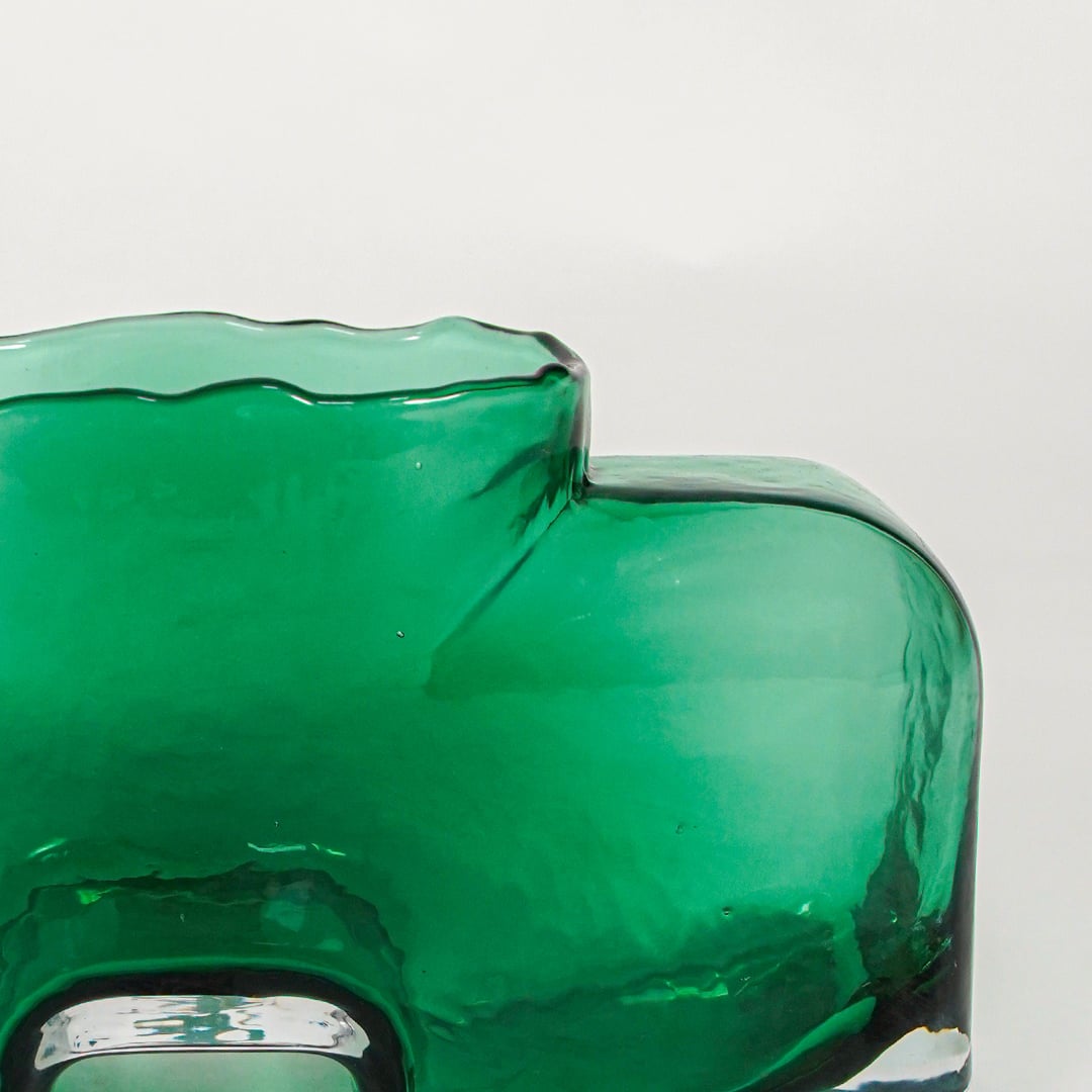 Close up view green sculpted glass vase with artistic shape modern decorative glass accent piece for shelf console styling home.
