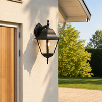 Classic black iron downward tapered cage glass wall lantern on exterior beige stucco next to wooden entryway door lighting.