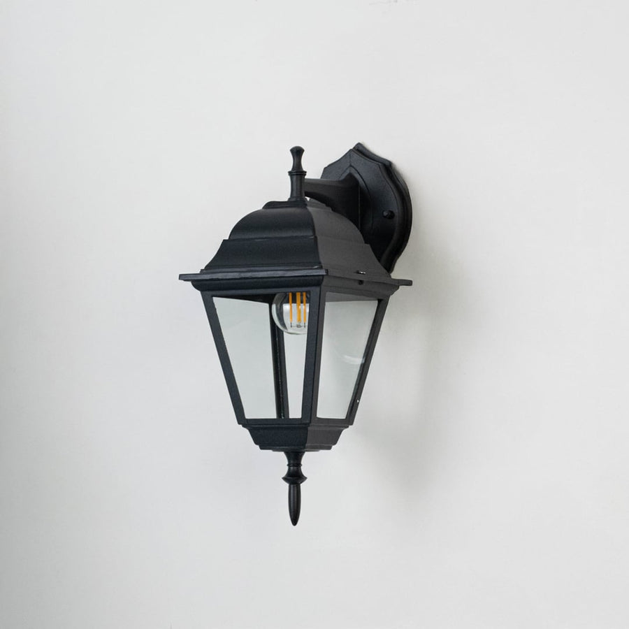 Black wall-mounted lantern light with matte finish and clear glass panels displayed on white background bulb turned off.