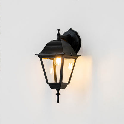 Black metal outdoor wall light on white background with warm glow for elegant exterior entryway decor.