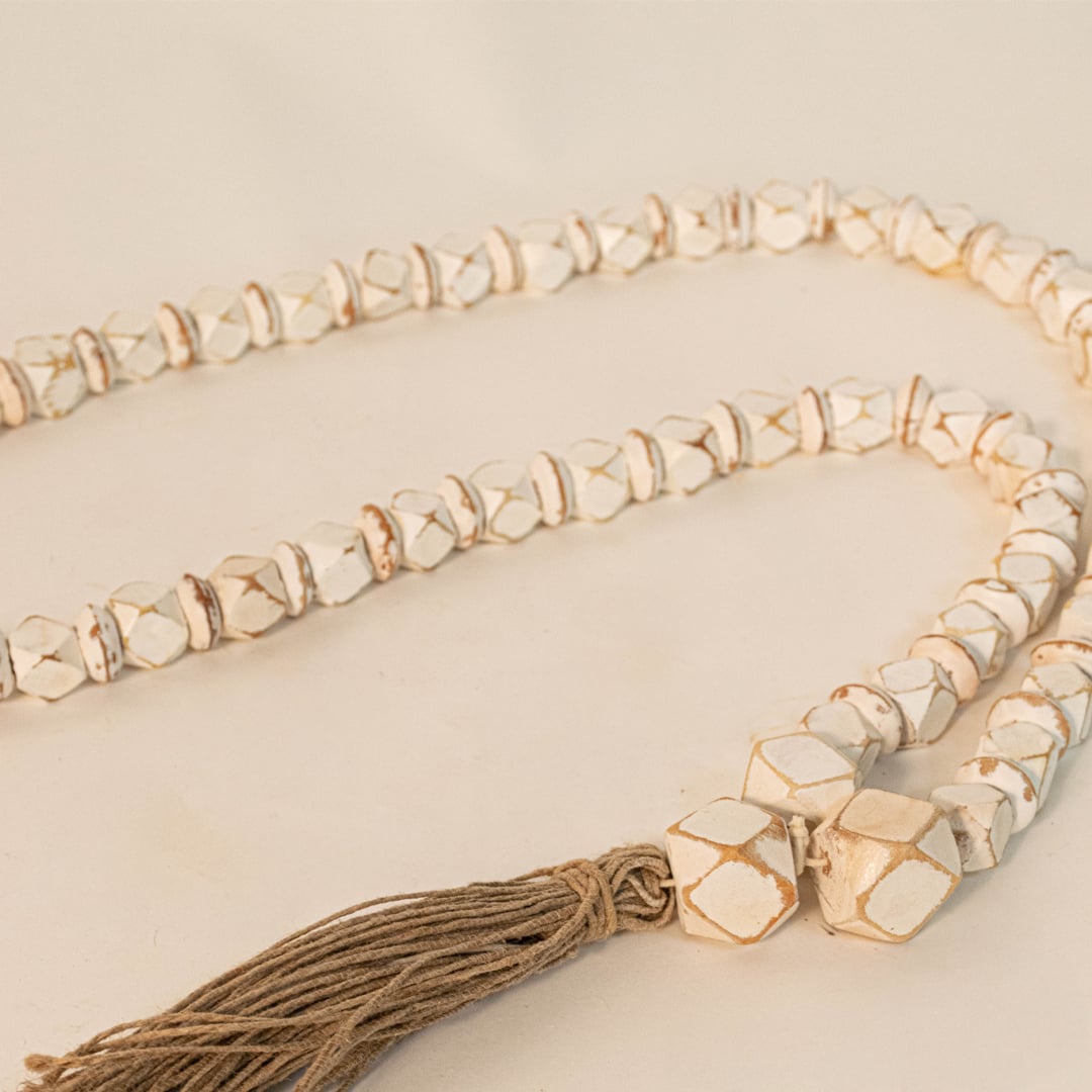 Close-up shot of white bead garland showing hand-painted bead texture and jute tassel craftsmanship.