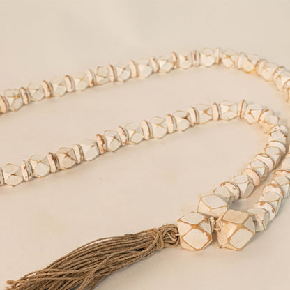 Close-up shot of white bead garland showing hand-painted bead texture and jute tassel craftsmanship.