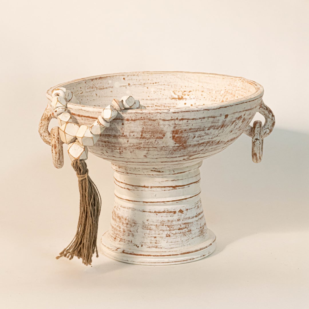 Handcrafted white bead garland draped over a rustic white ceramic bowl for modern boho home styling.