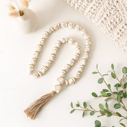 White bead garland styled beside a steaming cup of tea and vintage notebooks for calm aesthetic interior design.