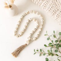 White bead garland styled beside a steaming cup of tea and vintage notebooks for calm aesthetic interior design.