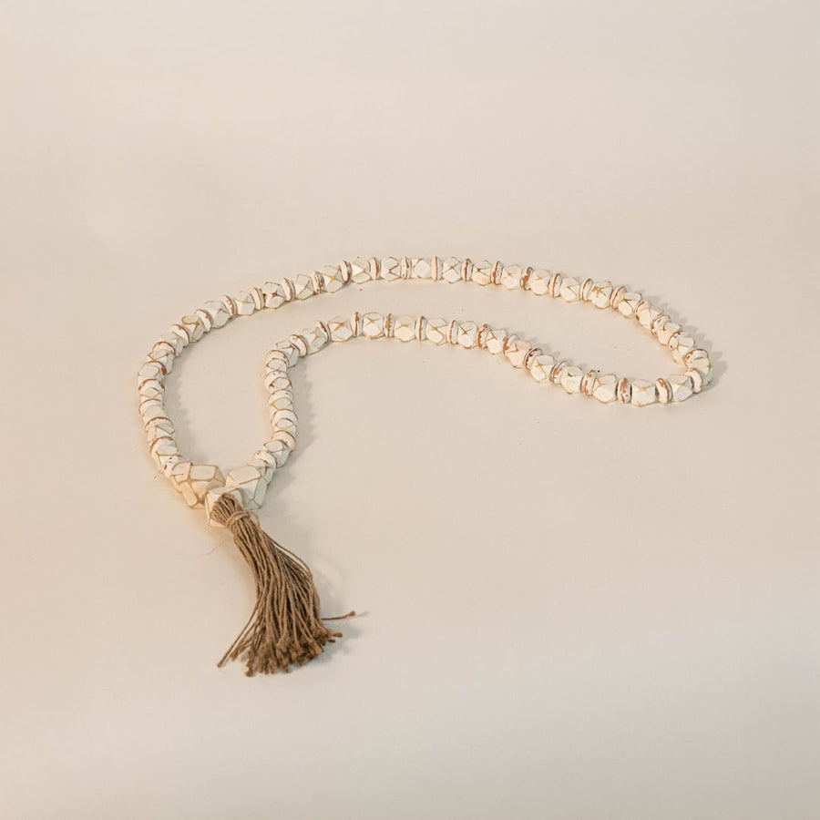 White bead garland placed on an off-white surface under soft lighting showcasing its natural and elegant appeal.