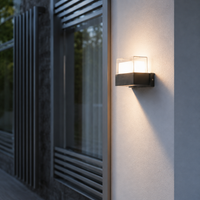 Modern black metal square dual glass cube wall sconce fixture on white stucco facade next to home window patio decoration.