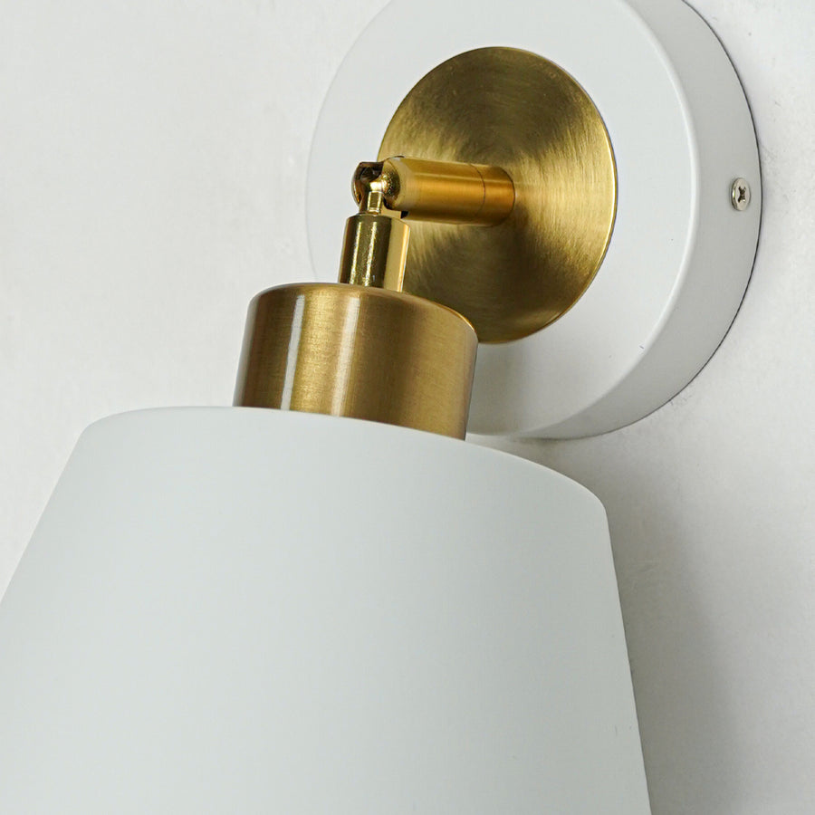 Closeup of white metal wall light with cone shade and gold holder showcasing smooth finish and premium detailing for modern decor.