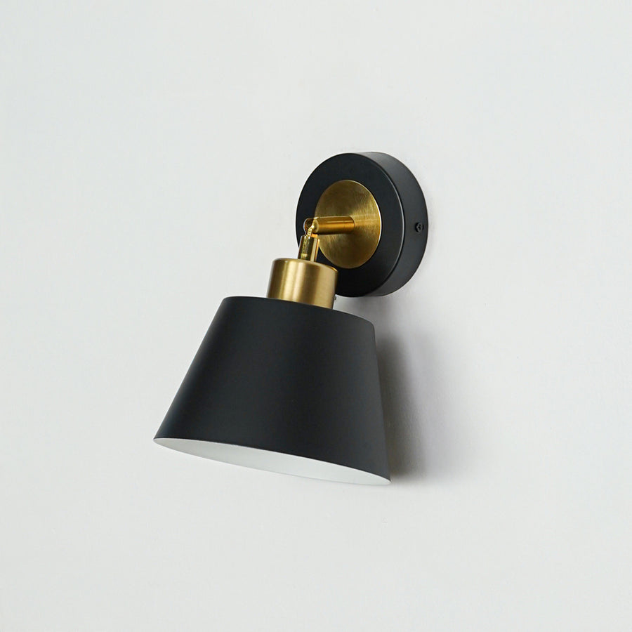 Modern black and gold metal wall light mounted on white wall for stylish bedroom and hallway decor styling.