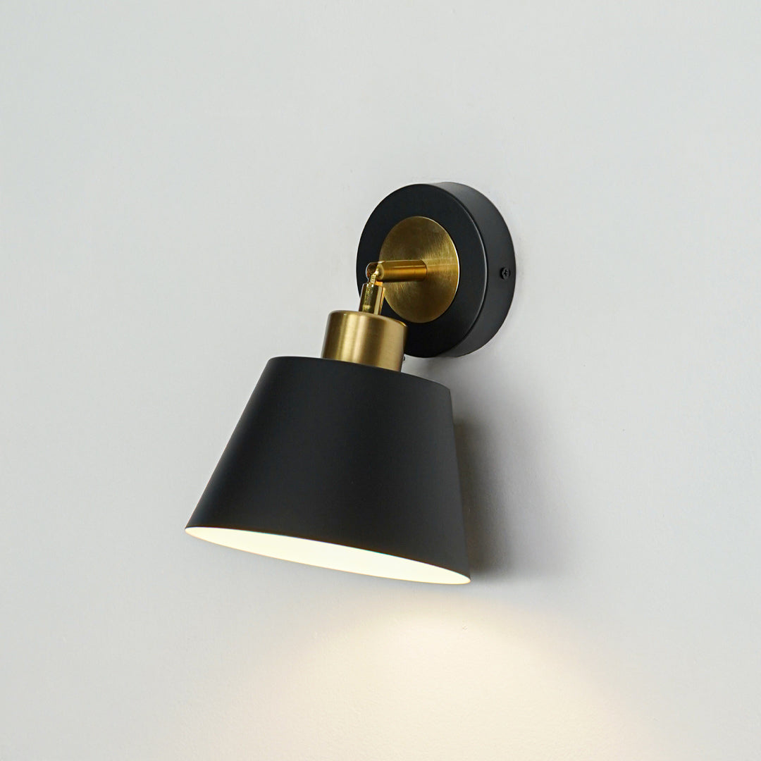 Closeup of black metal wall light with cone shade for modern bedroom hallway and living room decor styling.