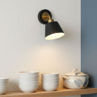 Modern black metal cone wall sconce light with brass accent above kitchen open shelving for contemporary home decor styling.