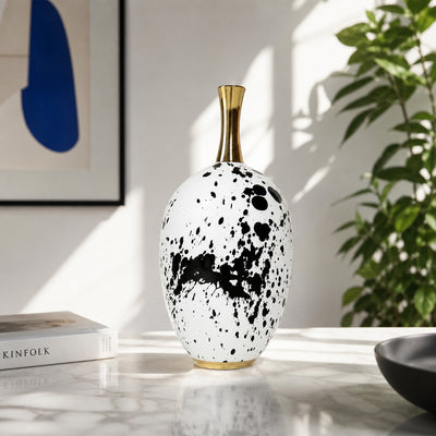 White and black ceramic decorative vase with gold neck placed on table for modern living room decor.